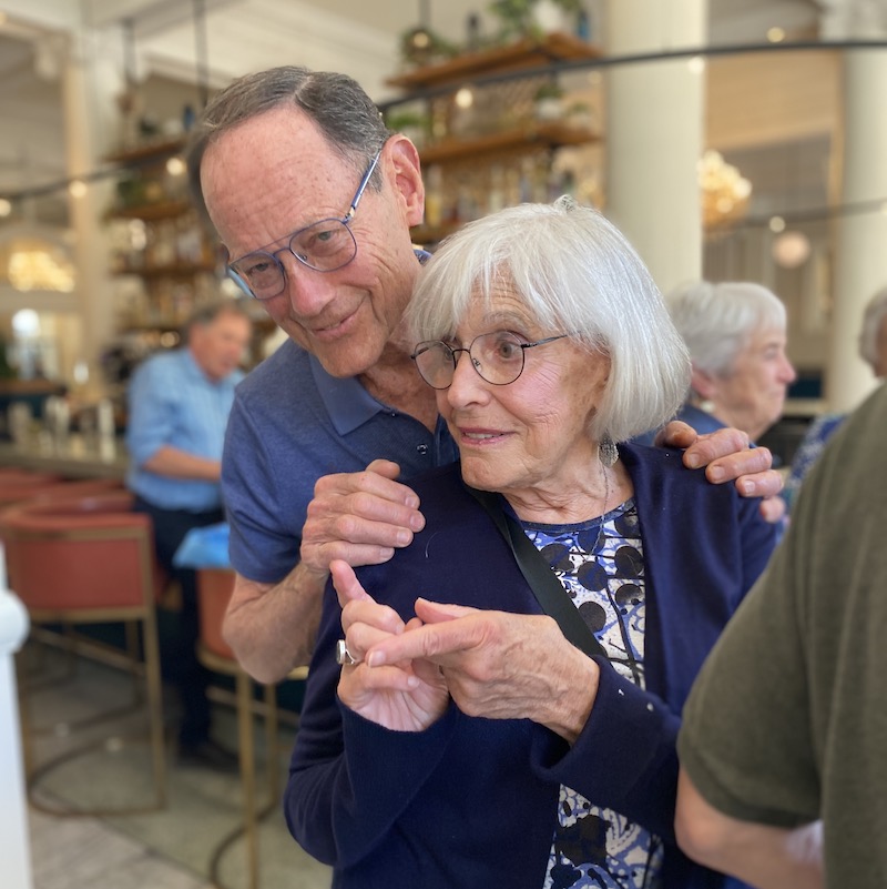 Mark Medress staring at camera with hands on shoulder of wife Marjorie