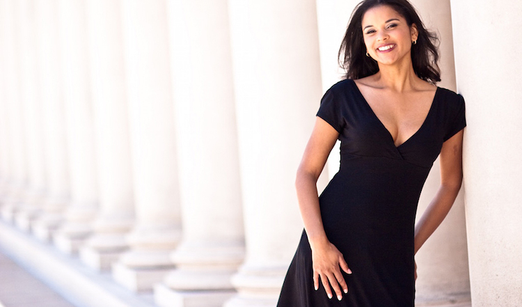 Sarita Cannon leaning against a column, smiling, and staring at the camera
