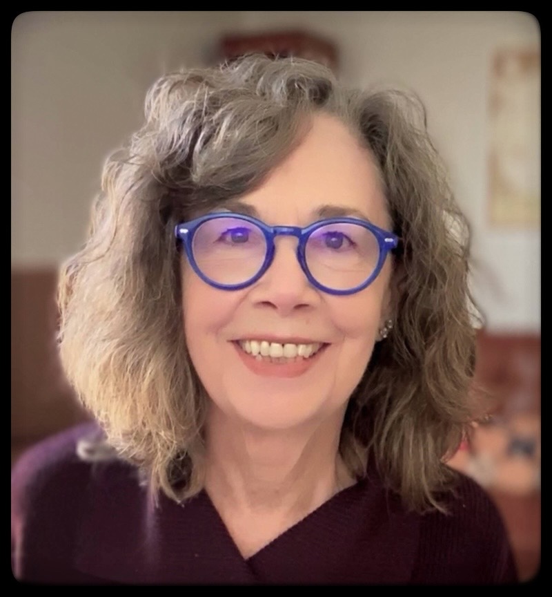 A smiling Kathleen Moran with dashing round blue glasses
